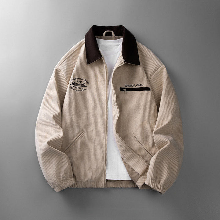 Beige Cordjacke für Herren mit Reißverschluss, dunklem Umlegekragen, Brusttasche und Stickerei auf grauem Hintergrund.