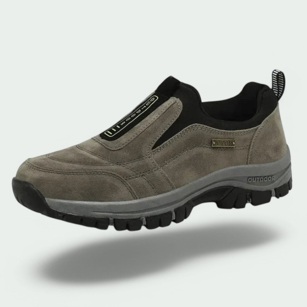 Grauer Herren-Slip-on-Sneaker aus Veloursleder mit gepolstertem Schaft und robuster, profilierter Outdoor-Laufsohle.