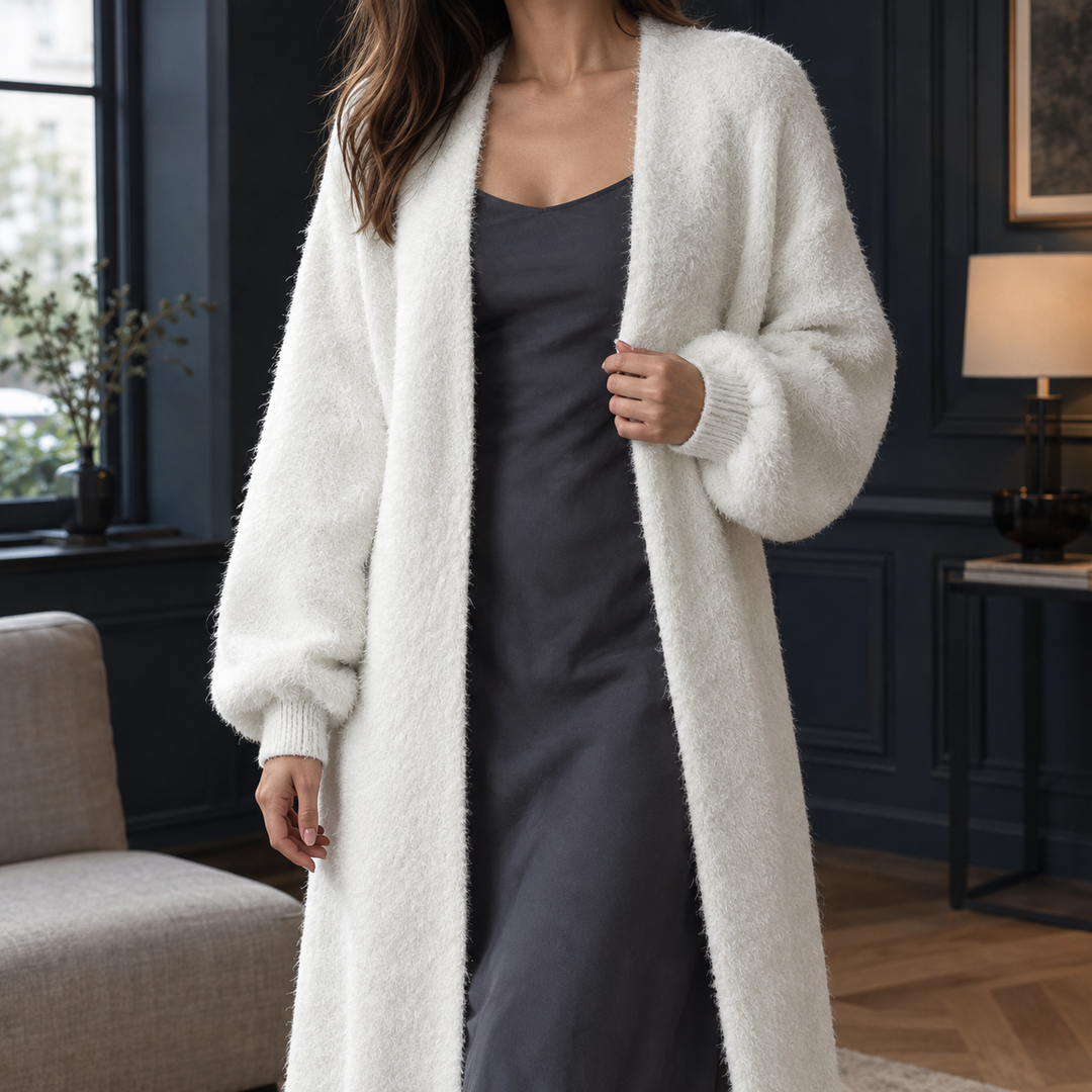 Lange, flauschige weiße Strickjacke in offenem Schnitt mit gerippten Bündchen über einem eleganten dunklen Kleid.