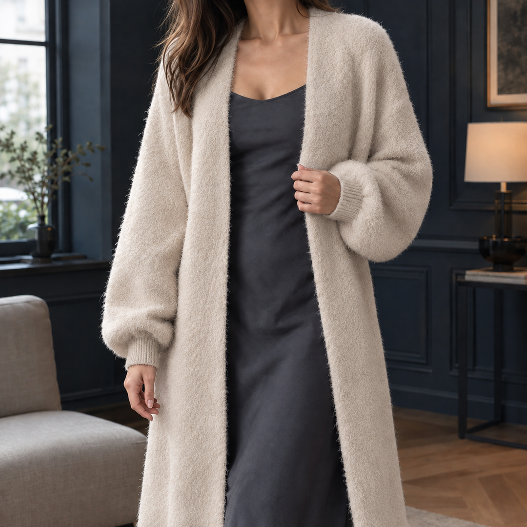 Lange, flauschige Strickjacke in Beige mit offenem Schnitt und gerippten Bündchen über einem dunklen Kleid.