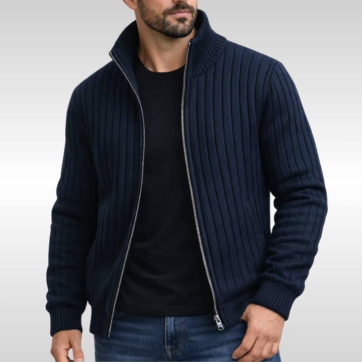 Dunkelblaue Herren-Strickjacke mit Reißverschluss, Stehkragen und gerippter Struktur über einem schwarzen T-Shirt.