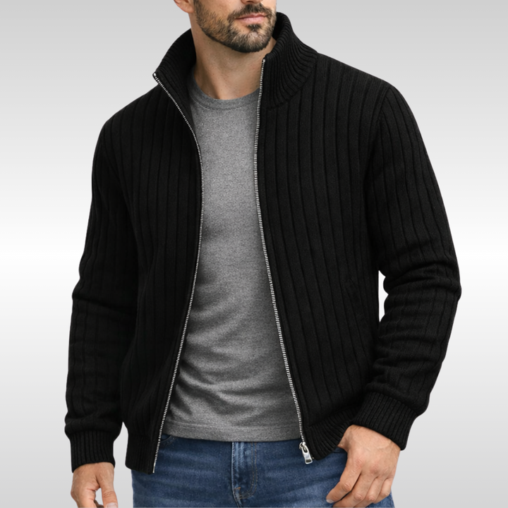 Schwarze Herren-Strickjacke mit Reißverschluss, Stehkragen und geripptem Strickmuster über einem grauen T-Shirt.