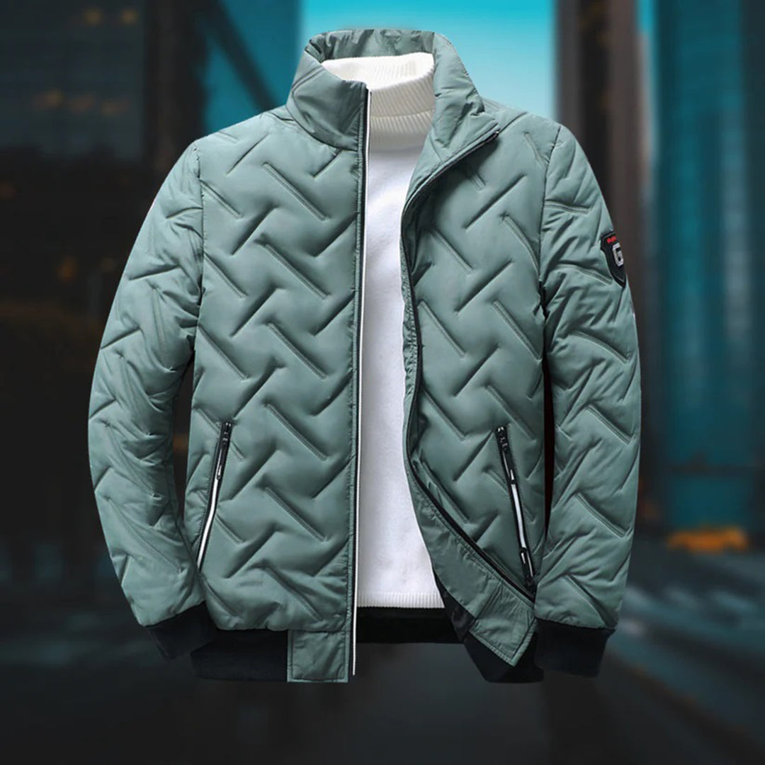 Salbeigrüne gesteppte Herrenjacke mit Zickzack-Muster, Stehkragen und Reißverschlusstaschen über weißem Rollkragenpullover.