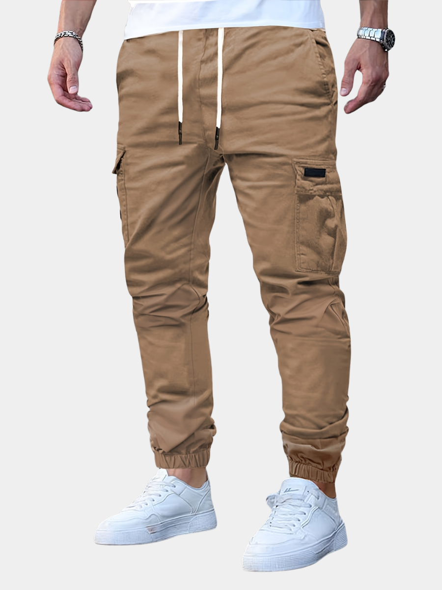 Beige Herren-Cargohose mit Kordelzug, seitlichen Taschen und elastischen Bündchen im modernen Jogger-Stil.