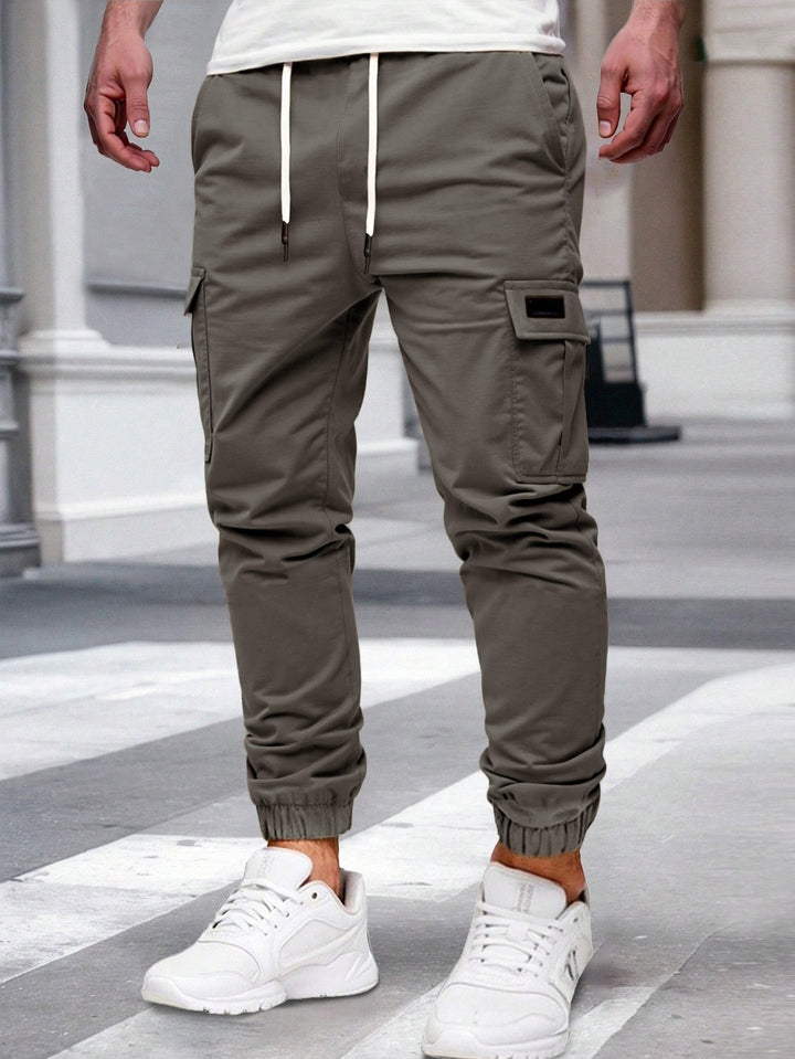 Olivgrüne Herren-Cargohose mit Kordelzug, seitlichen Taschen und elastischen Beinbündchen im modernen Jogger-Stil.