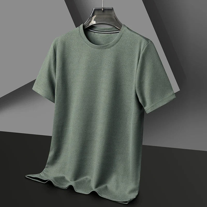 Salbeigrünes Herren-T-Shirt mit Waffelstrick-Struktur, Rundhalsausschnitt und lockerer Passform auf einem Kleiderbügel.