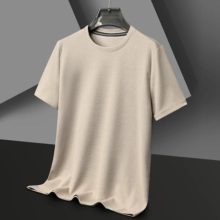 Beiges Herren-T-Shirt mit Waffelstrick-Struktur, Rundhalsausschnitt und lockerer Passform auf einem Kleiderbügel.