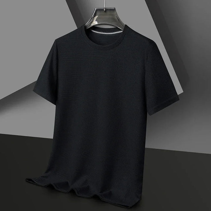 Schwarzes Herren-T-Shirt mit Waffelstrick-Struktur, Rundhalsausschnitt und lockerer Passform auf einem Kleiderbügel.