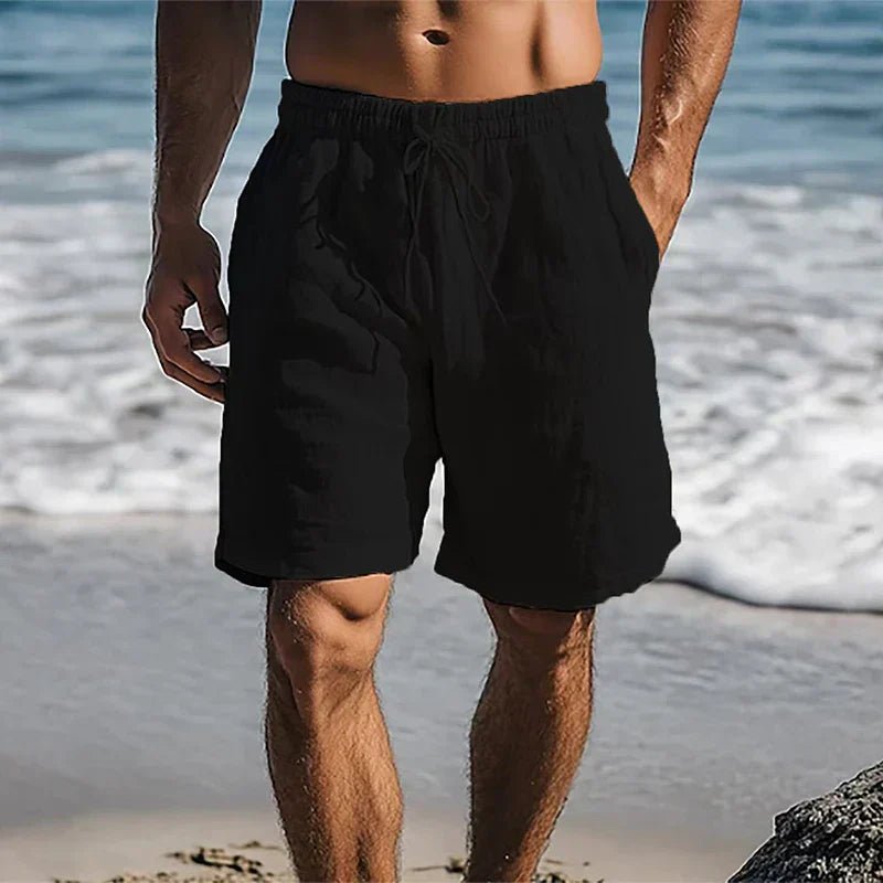 Schwarze Herren-Leinenshorts mit Kordelzug und Seitentaschen in lockerer Passform am Strand.
