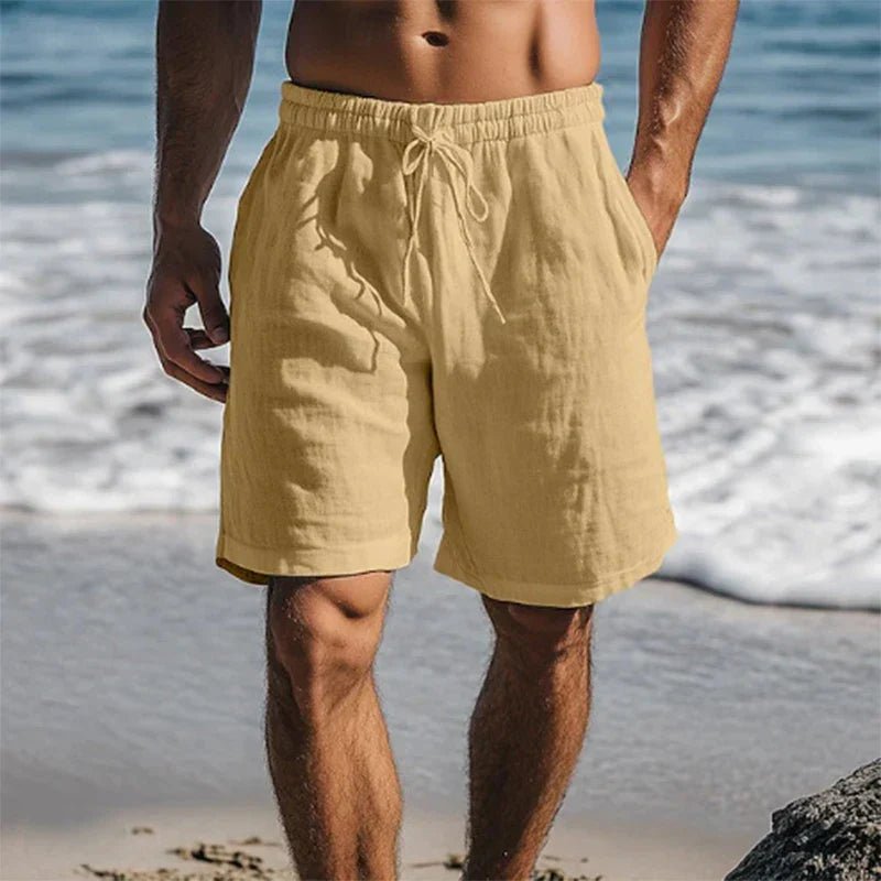 Beigefarbene Herren-Leinenshorts mit Kordelzug, elastischem Bund und Seitentaschen am Strand.