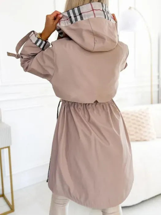 Beigefarbene Damen-Kapuzenjacke mit kariertem Innenfutter, Kordelzug an der Taille und Reißverschluss.
