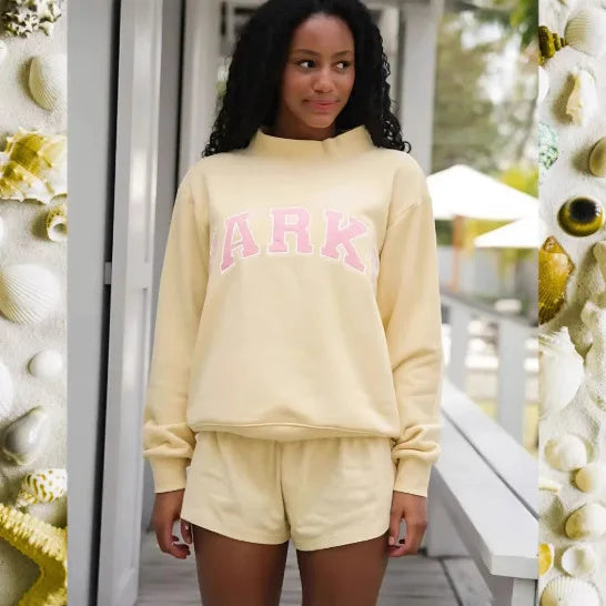 Hellgelber Oversized-Pullover mit rosa Schriftzug-Print und passender Shorts aus weichem Sweat-Material.