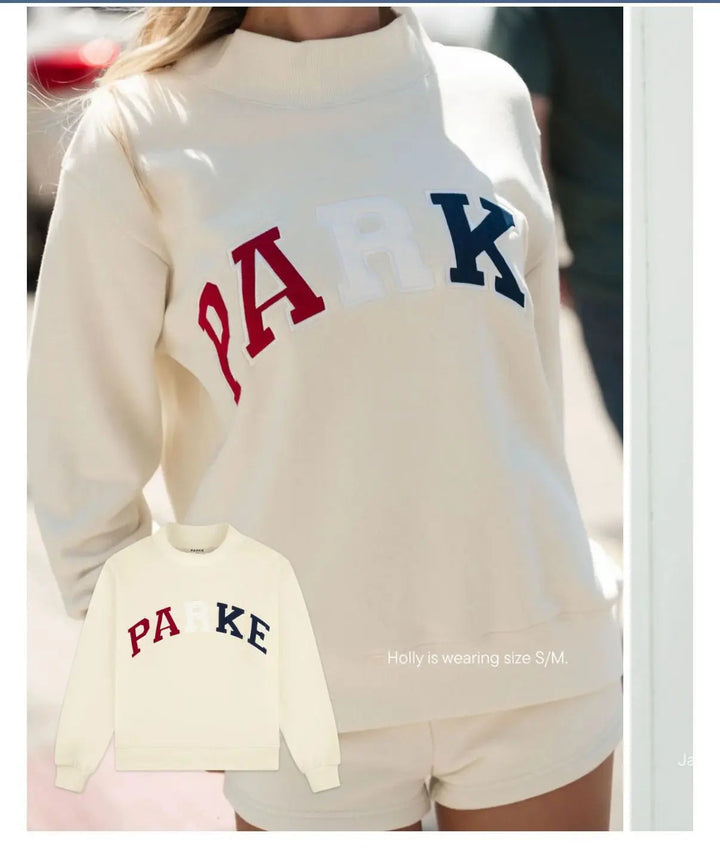 Cremeweißer Oversized-Pullover mit Stehkragen und buntem PARK-Schriftzug aus weichem Sweatstoff.