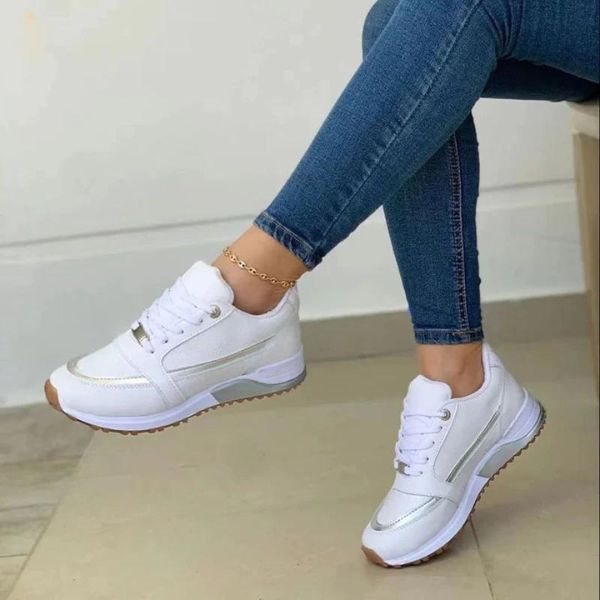 Weißer Damen-Plateau-Sneaker mit Schnürung, metallischen Akzenten und robuster Sohle, getragen zu einer blauen Jeans.