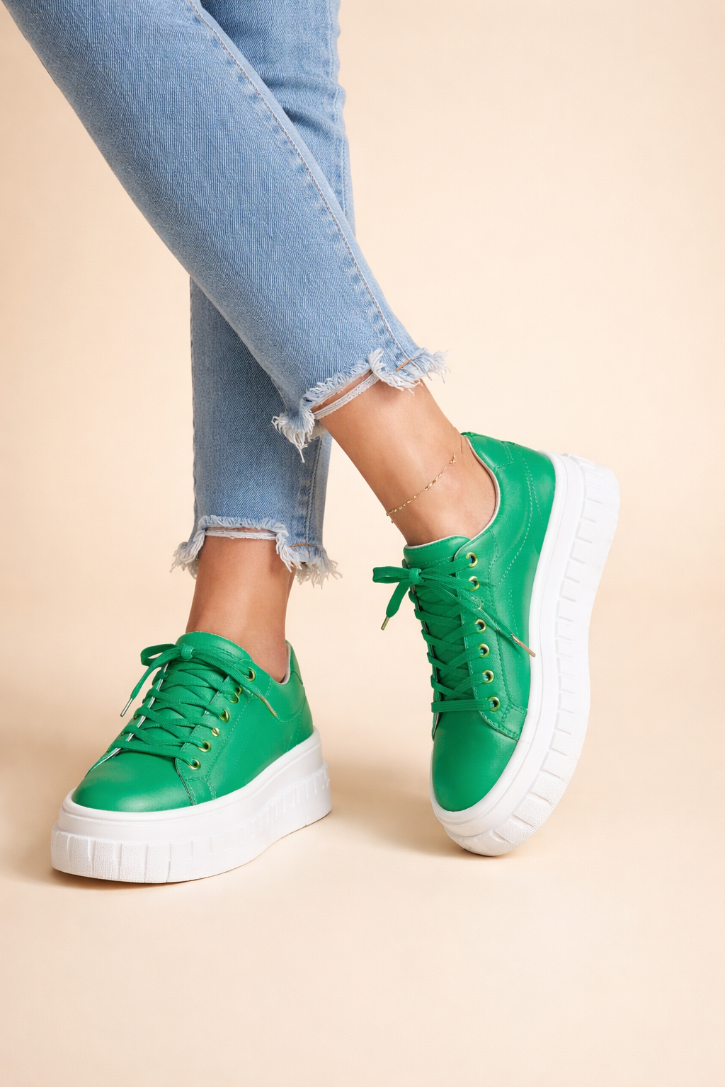 Grüne Selin Plateau-Sneaker mit Schnürung und markanter weißer Sohle, kombiniert mit einer hellblauen Jeans.