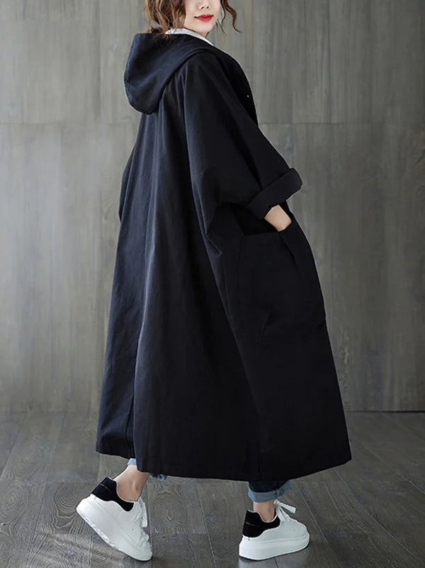 Schwarzer Oversized-Mantel mit Kapuze, langen Ärmeln und aufgesetzten Taschen im lässigen, modernen Schnitt.