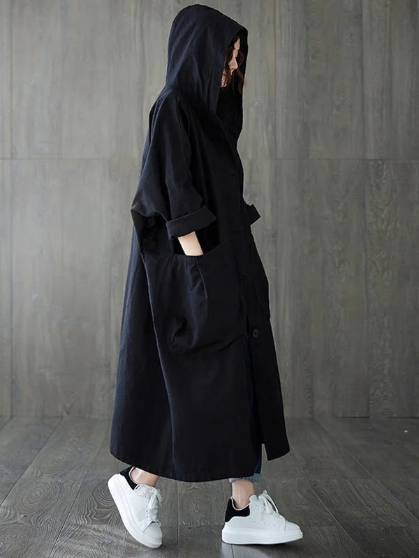 Schwarzer, langer Oversized-Mantel mit Kapuze, Knopfleiste und großen aufgesetzten Taschen im lässigen Stil.