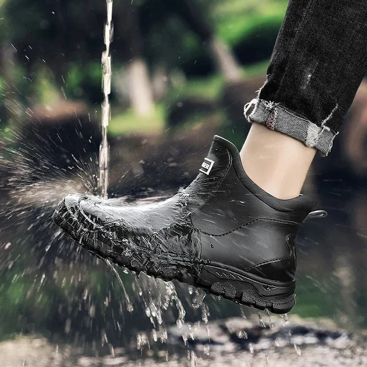 Schwarze wasserdichte Damen-Regenstiefeletten mit rutschfester Profilsohle und Slip-on-Design bei Regen.