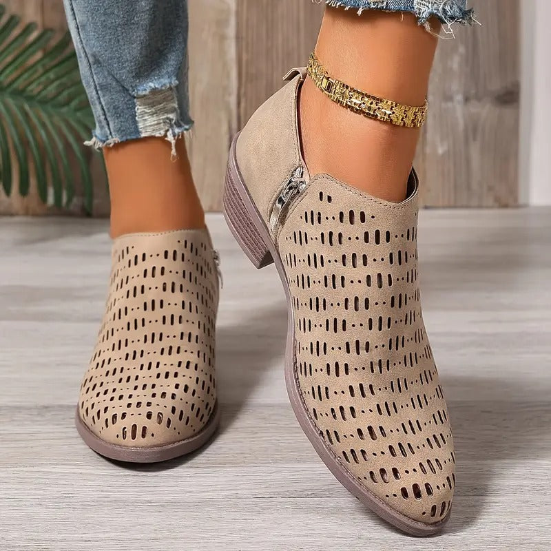 Beigefarbene Damen-Stiefeletten mit Cut-Out-Muster, seitlichem Reißverschluss und niedrigem Blockabsatz.