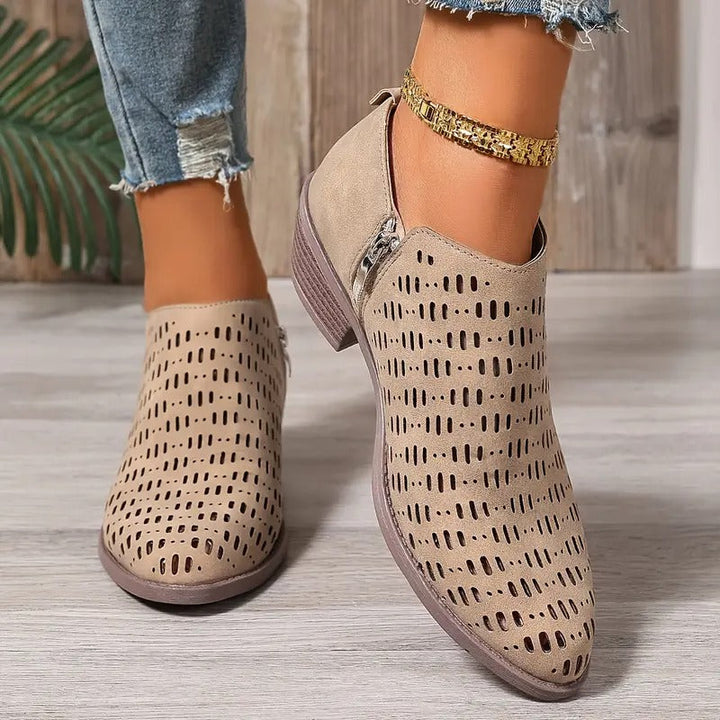 Beigefarbene Damen-Stiefeletten mit Cut-Out-Muster, seitlichem Reißverschluss und niedrigem Blockabsatz.