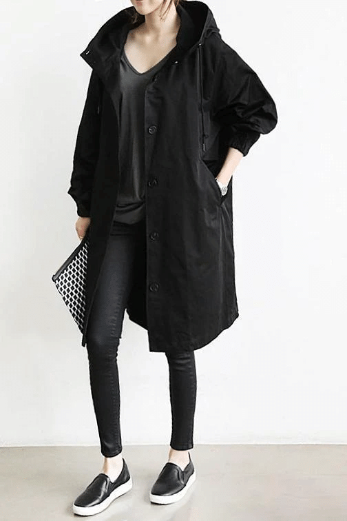 Schwarze Oversized-Windjacke für Damen mit Kapuze, Knopfleiste und elastischen Ärmelbündchen im lässigen Schnitt.