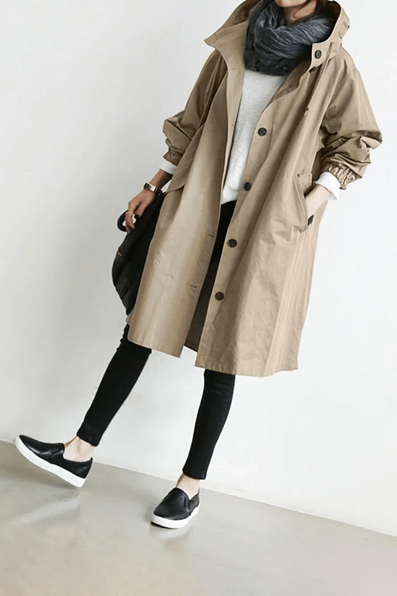 Beigefarbene Oversized-Windjacke für Damen mit Kapuze, Knopfleiste, Seitentaschen und elastischen Ärmelbündchen.