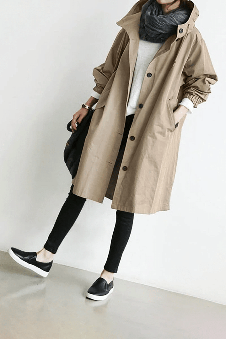Beigefarbene Oversized-Windjacke für Damen mit Kapuze, Knopfleiste, Seitentaschen und elastischen Ärmelbündchen.