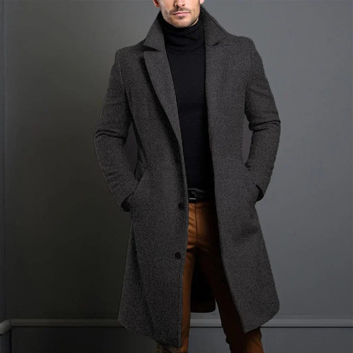 Eleganter, dunkelgrauer Herren-Wintermantel mit Reverskragen, knielangem Schnitt und strukturierter Oberfläche.