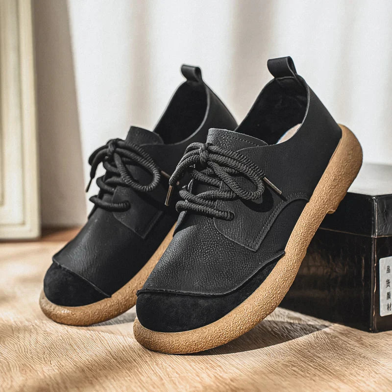 Schwarze Herren-Schnürschuhe mit strukturierter Oberfläche, Zuglasche und markanter, profilierter Laufsohle in Beige.
