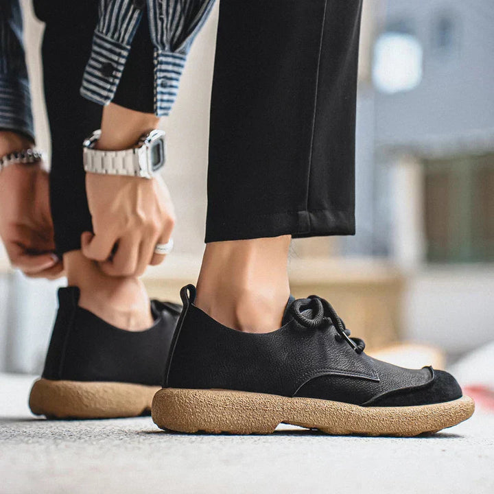 Schwarze Theo Herren-Schnürschuhe mit strukturierter Oberfläche, klassischer Schnürung und markanter, beiger Profilsohle.