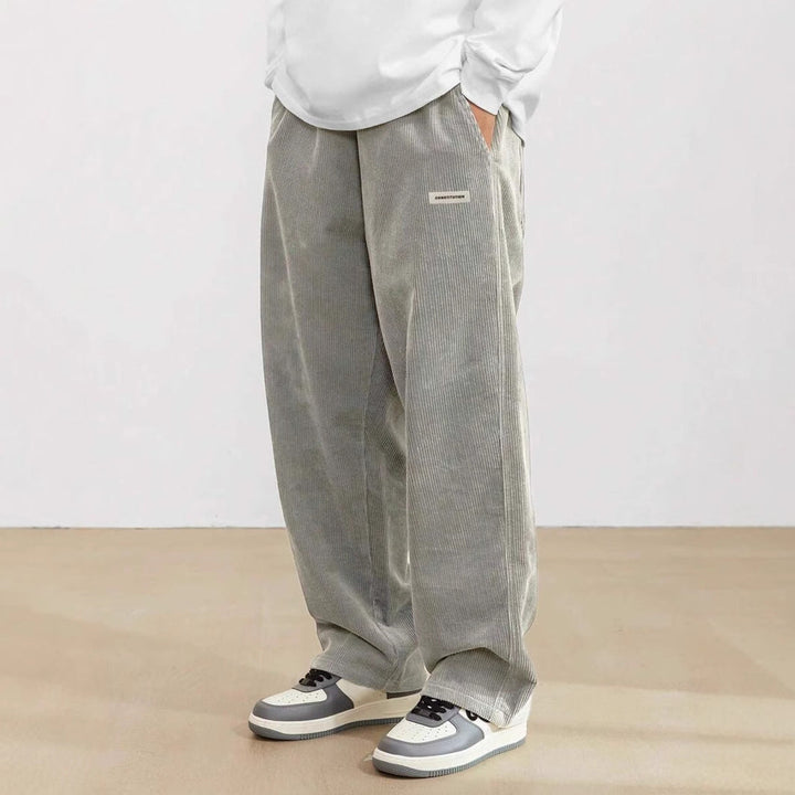 Graue Herren-Cordhose mit weitem Schnitt, elastischem Bund und praktischen Seitentaschen für einen lässigen Look.