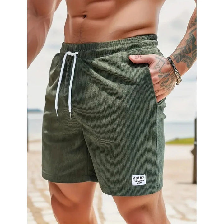 Olivgrüne Herren-Shorts aus Kord mit weißem Kordelzug, elastischem Bund und seitlichem Logo-Patch.