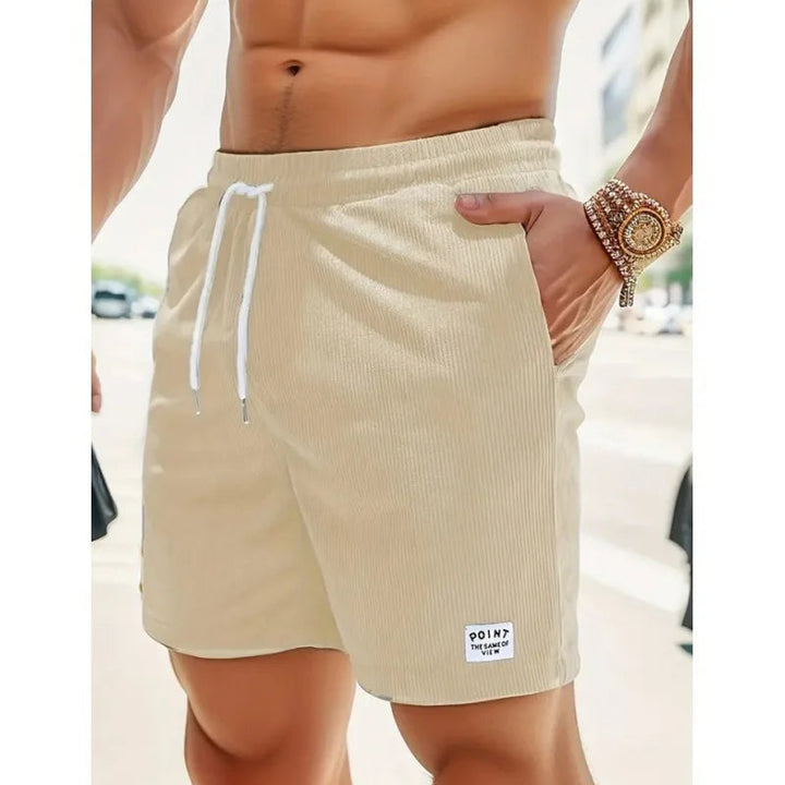 Beigefarbene Herren-Shorts aus Kord mit weißem Kordelzug, elastischem Bund und kleinem Logo-Patch am Saum.
