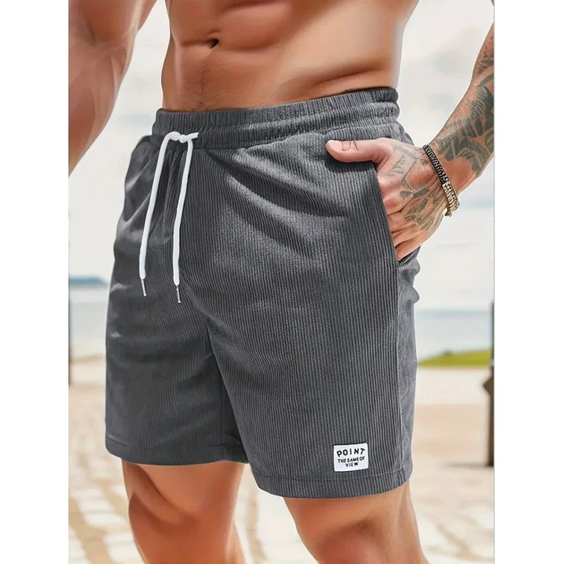 Dunkelgraue Herren-Shorts aus Kord mit weißem Kordelzug, elastischem Bund und kleinem Logo-Patch am Saum.