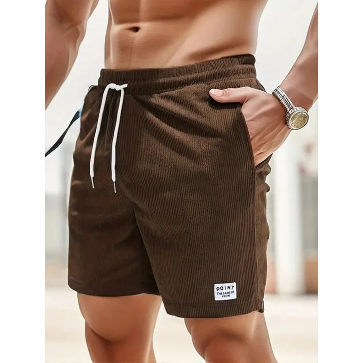 Braune Kordel-Shorts für Herren mit weißem Kordelzug, elastischem Bund, Seitentaschen und kleinem Logo-Patch.