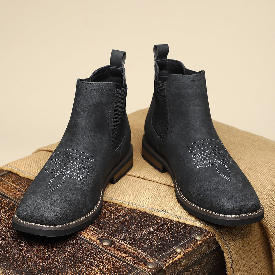 Schwarze Herren-Chelsea-Boots im Western-Stil aus Kunstleder mit Ziernähten, elastischen Einsätzen und Blockabsatz.