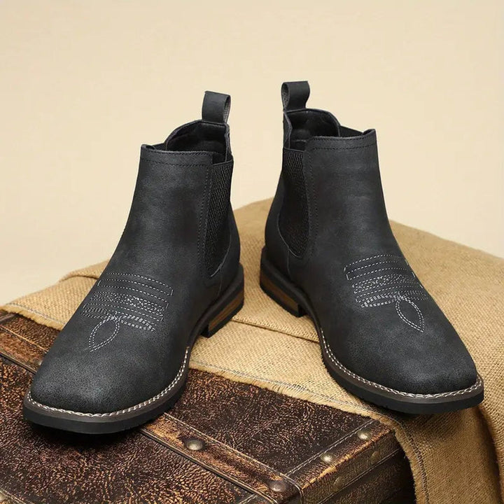 Schwarze Herren-Chelsea-Boots im Western-Stil aus Kunstleder mit Ziernähten, elastischen Einsätzen und Blockabsatz.