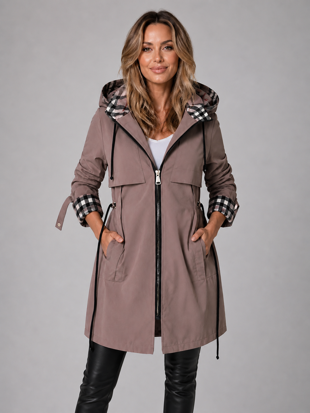 Moderne, lange Damenjacke in Taupe mit Kapuze, Kordelzug in der Taille und stilvollen karierten Akzenten an Ärmeln und Kapuze.