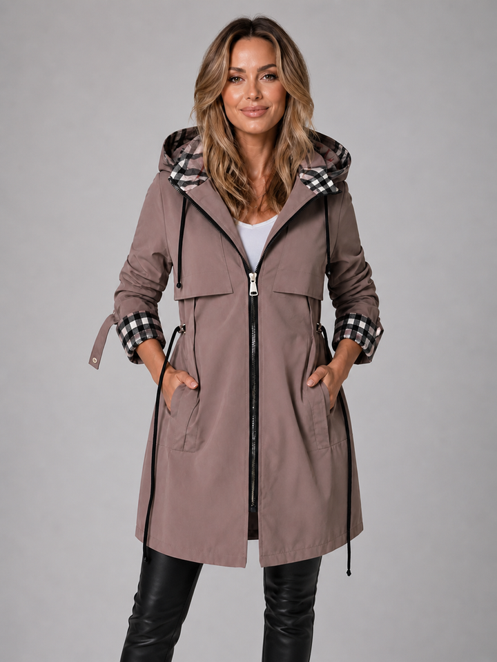 Moderne, lange Damenjacke in Taupe mit Kapuze, Kordelzug in der Taille und stilvollen karierten Akzenten an Ärmeln und Kapuze.