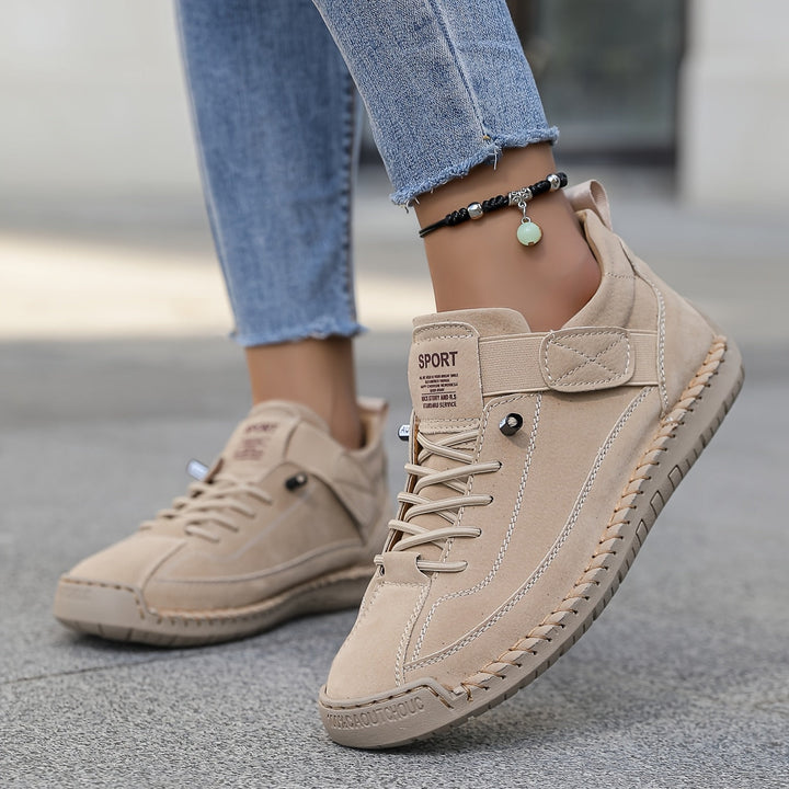 Beigefarbene Damen-Sneaker aus Wildleder mit Schnürung, Klettverschluss, markanten Ziernähten und flacher, profilierter Sohle.