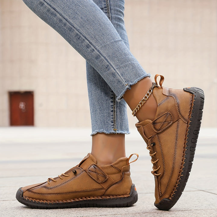 Braune Damen-Sneaker aus Leder mit Schnürung, Klettverschluss, dekorativen Ziernähten und flacher, profilierter Sohle.