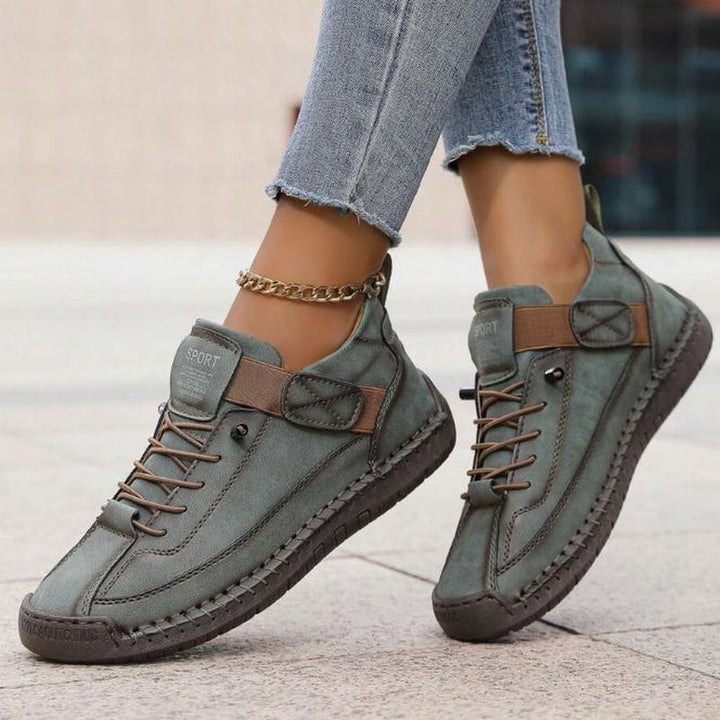 Graue Damen-Sneaker mit Schnürung, Klettverschluss, Ziernähten und flacher, profilierter Sohle im modernen Look.