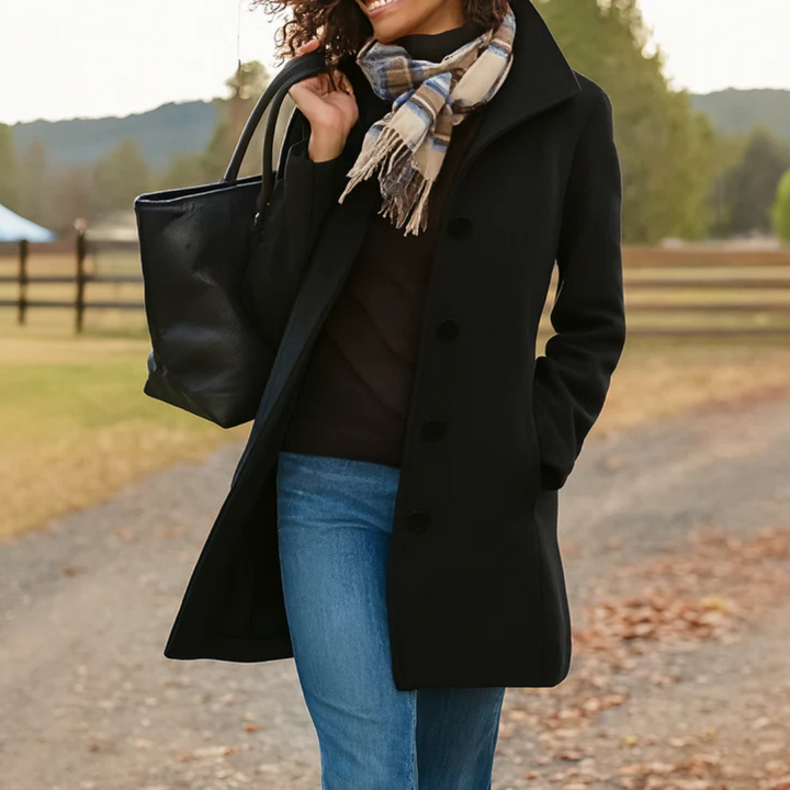 Schwarzer Damen-Wintermantel mit Knopfleiste, Umlegekragen und Seitentaschen, kombiniert mit Schal und Tasche.