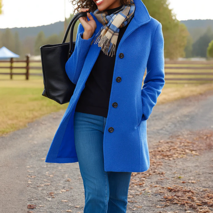 Eleganter blauer Damen-Wintermantel mit Knopfleiste, Umlegekragen und Seitentaschen, kombiniert mit schwarzer Tasche.
